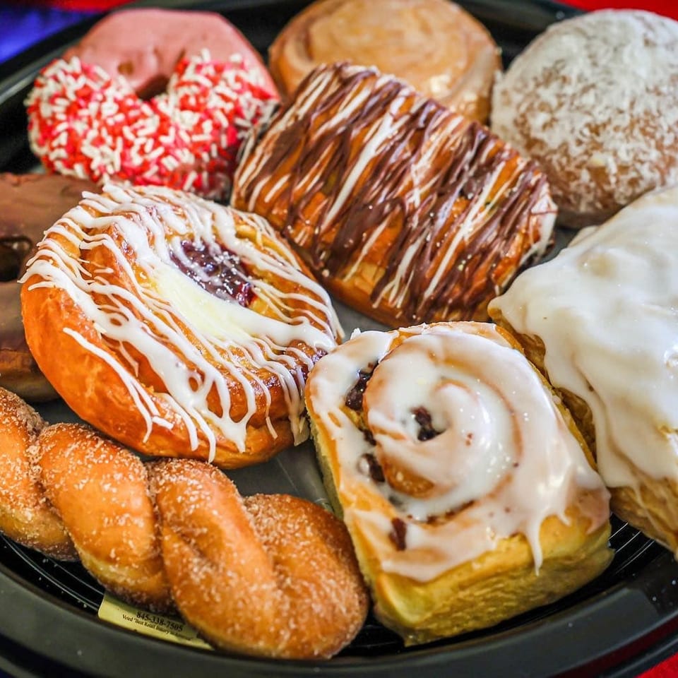 Assorted glazed and chocolate-drizzled donuts arranged on a black serving platter.