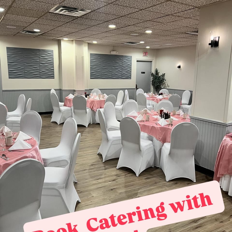 Elegant restaurant dining room with pink tablecloths, white-covered chairs, folded napkins, and textured wall panels.